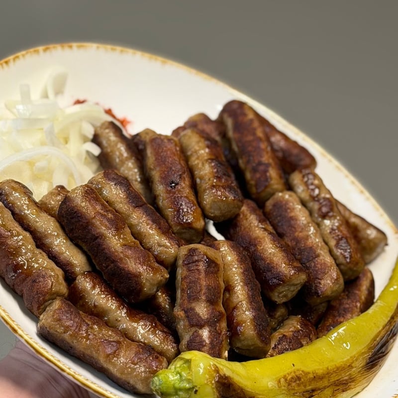 Ćevapčići vom Grill mit Zwiebeln und gegrillter Peperoni